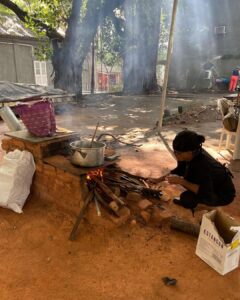 Mulher indígena preparando alimento em fogão de barro durante atividade da Cozinha das Tradições, representando tecnologia indígena e saberes tradicionais no Brasil